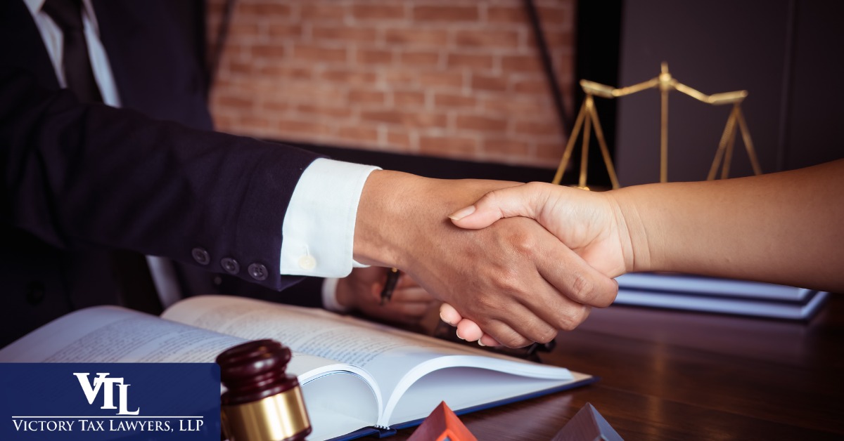Attorney shaking hands with a client beside a set of scales and a gavel
