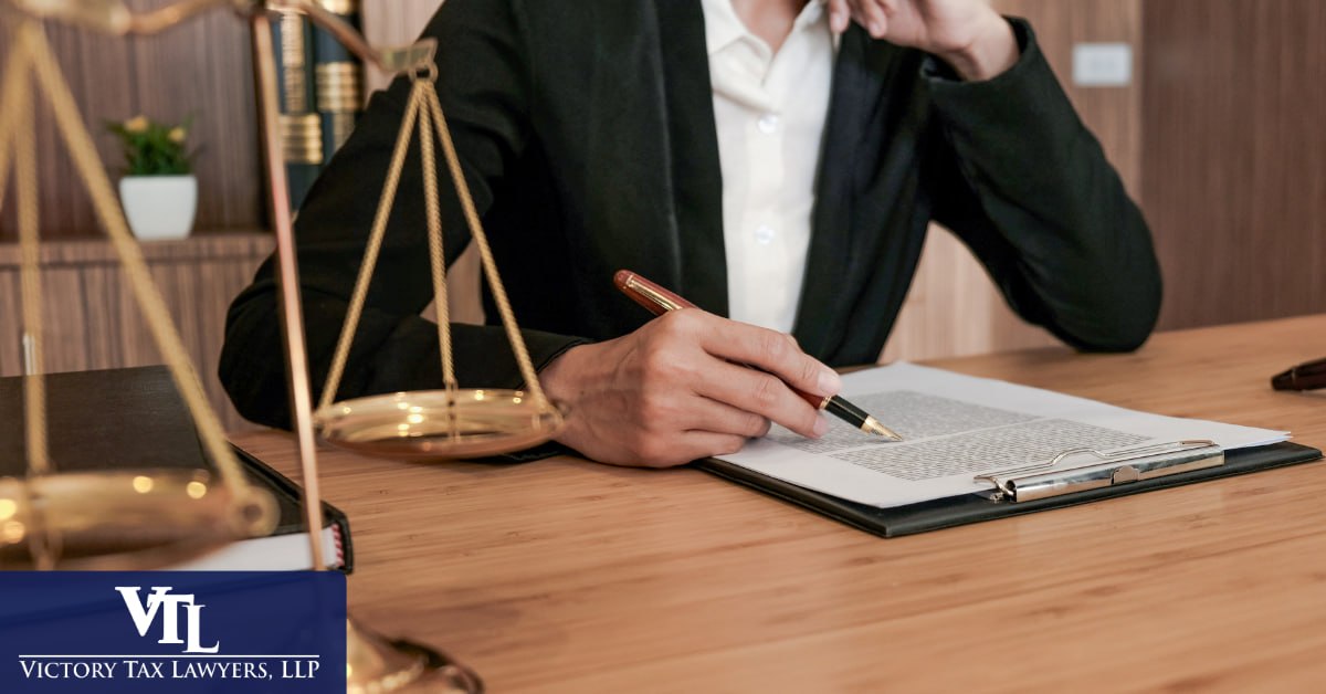 Tax attorney reviewing a legal document at a desk beside a set of scales