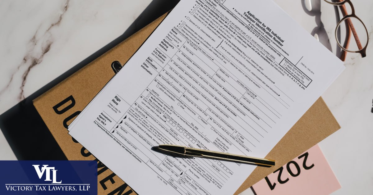 An IRS application form and documents on a desk with a pen, Victory Tax Lawyers