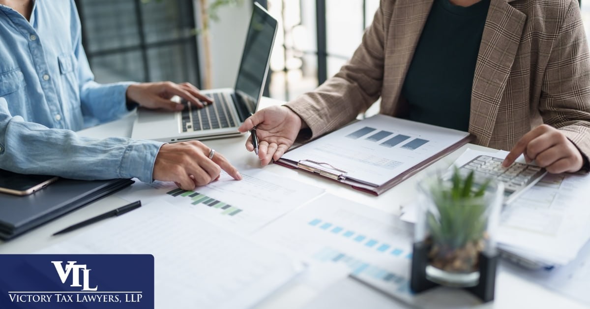 Two people reviewing financial documents together at a desk, Victory Tax Lawyers