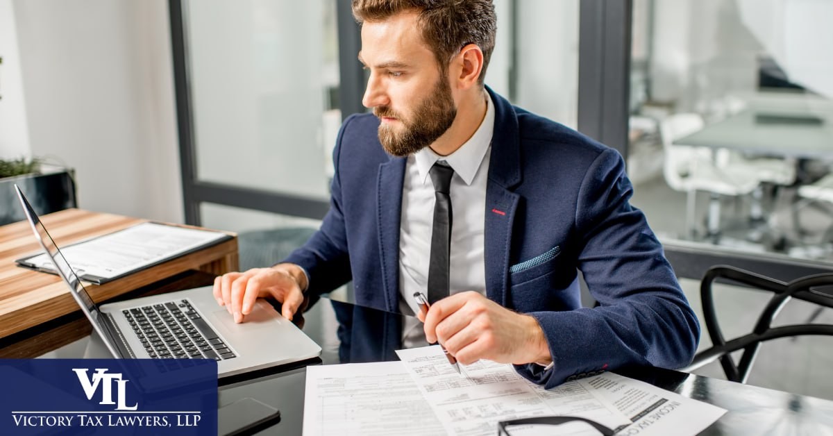 A man reviewing an income tax return at a laptop, Victory Tax Lawyers