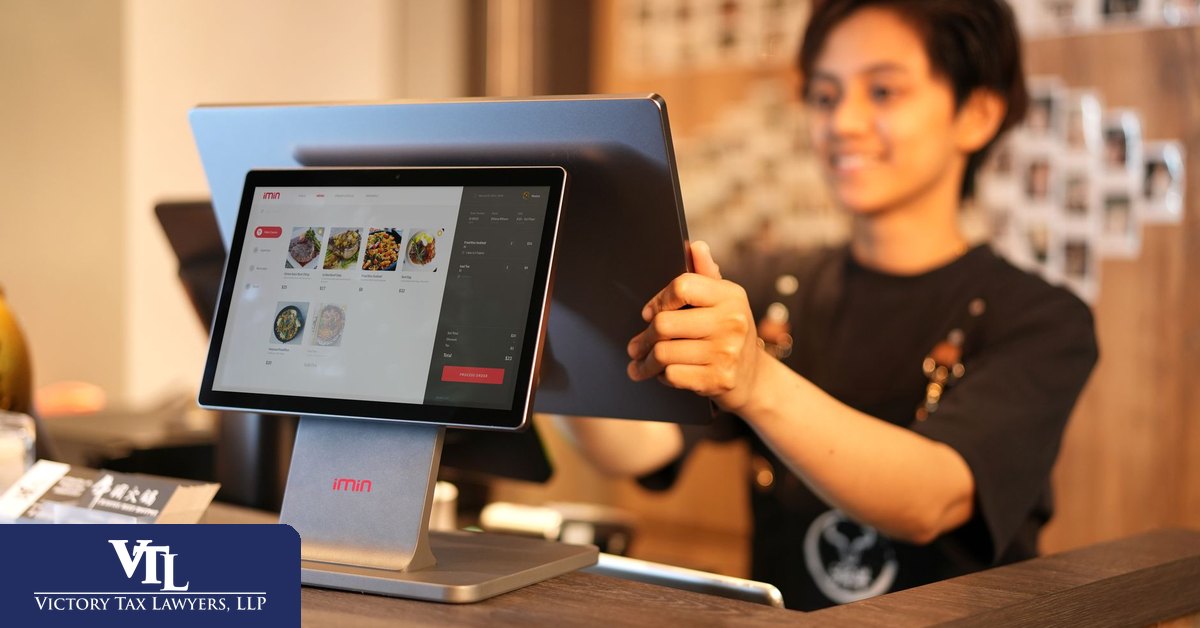 Cashier ringing a sale through a point-of-sale system in a California business