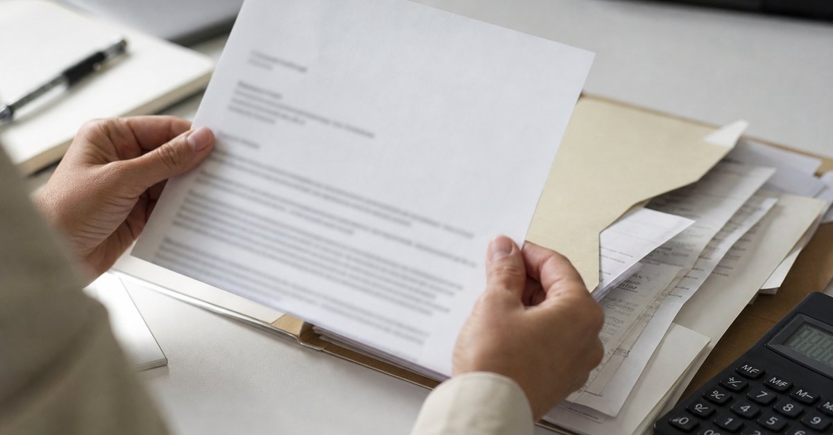 Taxpayer reading a New York State Tax Department audit letter beside a folder of receipts and a calculator